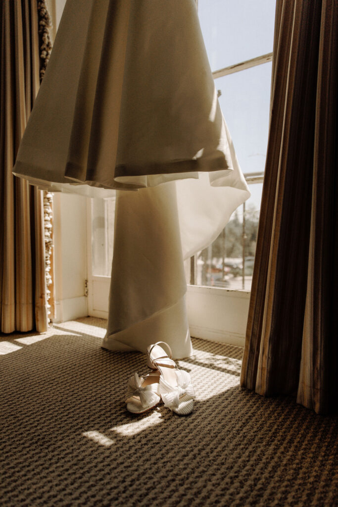 wedding dress hanging with brides shoes